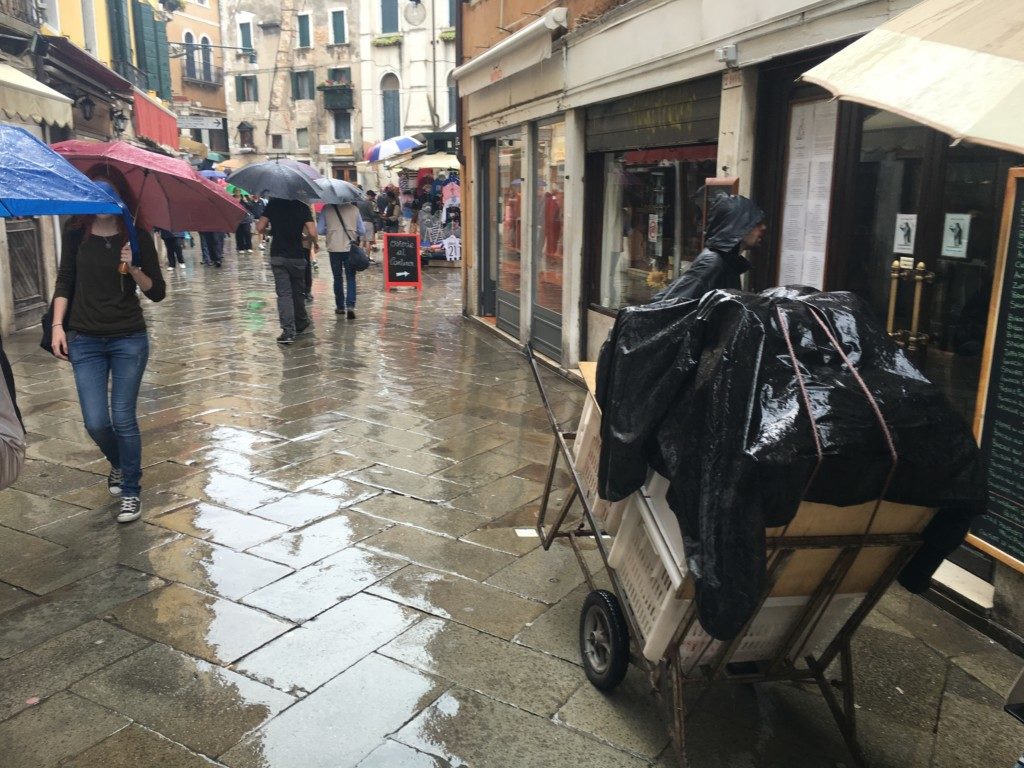 Tak wyglądają dostawy towaru do sklepów w Wenecji. Tragarze dźwigają ciężkie przyczepki.