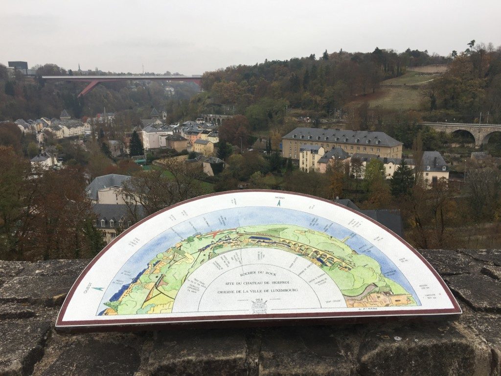 W oddali widać most Pont Grand-Duchesse Charlotte, zwany też Czerwonym Mostem. Łączący dawną Twierdzę Luksemburg z nowoczesną dzielnicą Kirchberg. Most oddano do użytku w 1965 roku. Wykonany ze stali posiada 74 m wysokości (przerzucony jest nad dzielnicą Pfaffenthal), 25,07 m szerokości, a jego łączna długość wynosi 355 m.